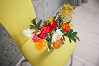 Photo of Vase with beautiful ranunculus flowers on chair indoors