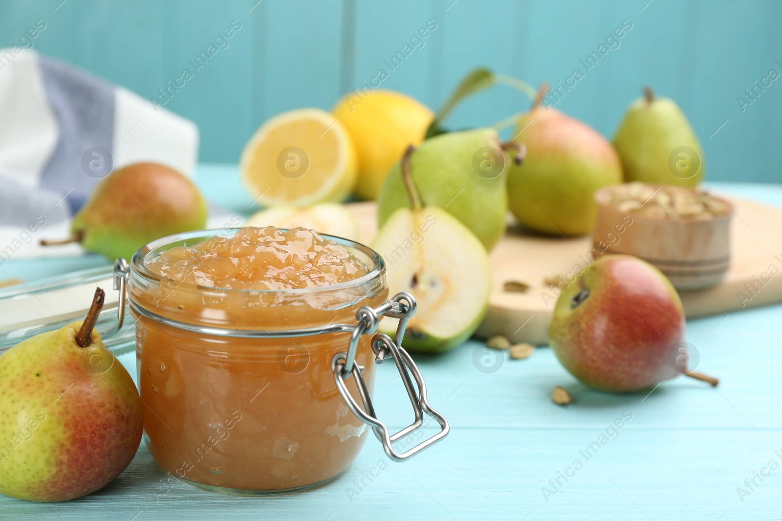 Photo of Tasty homemade pear jam and fresh fruits on light blue wooden table. Space for text