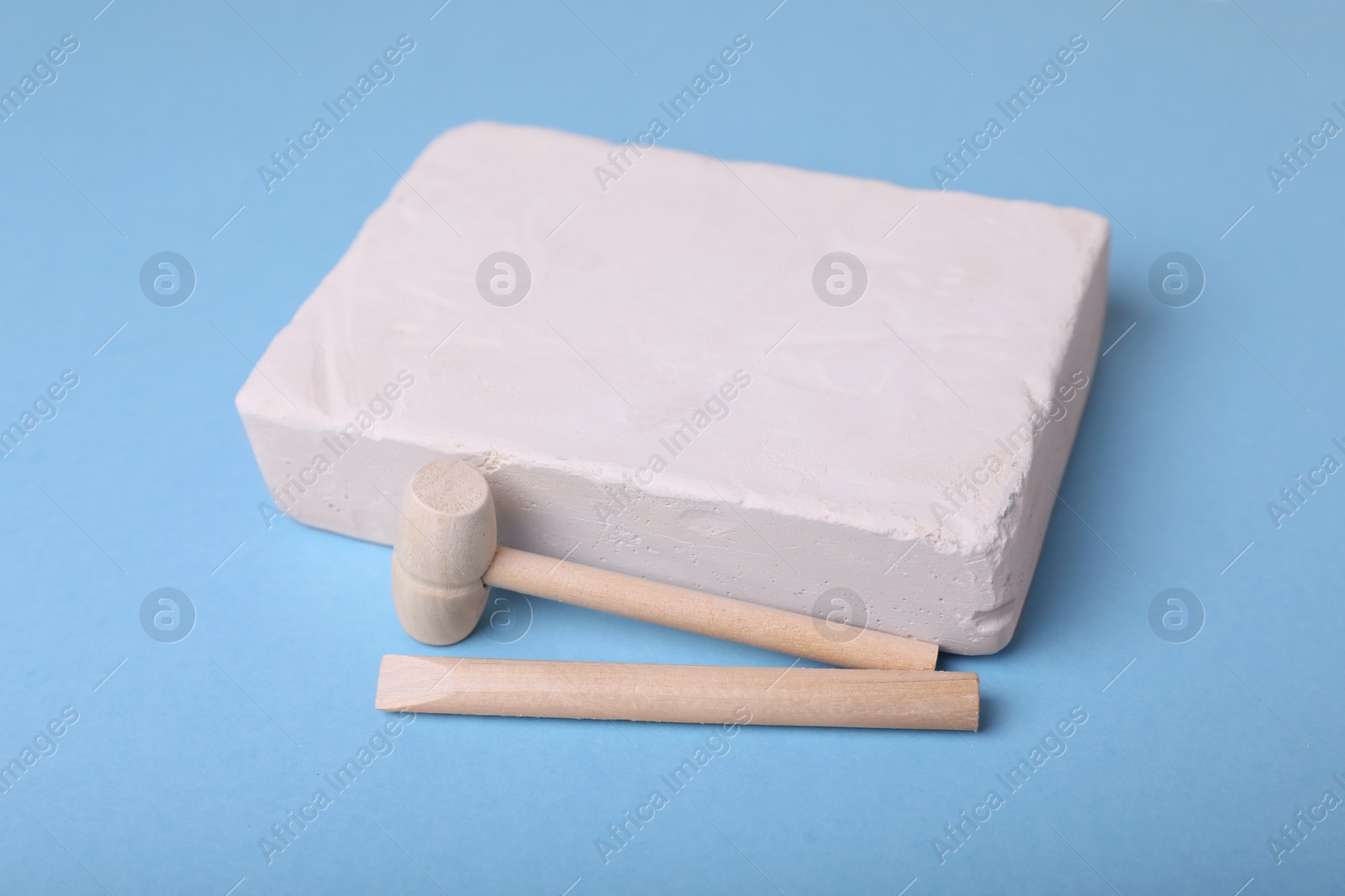 Photo of Educational toy for motor skills development. Excavation kit (plaster and digging tools) on light blue background, closeup