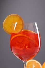 Glass of tasty Aperol spritz cocktail against gray background