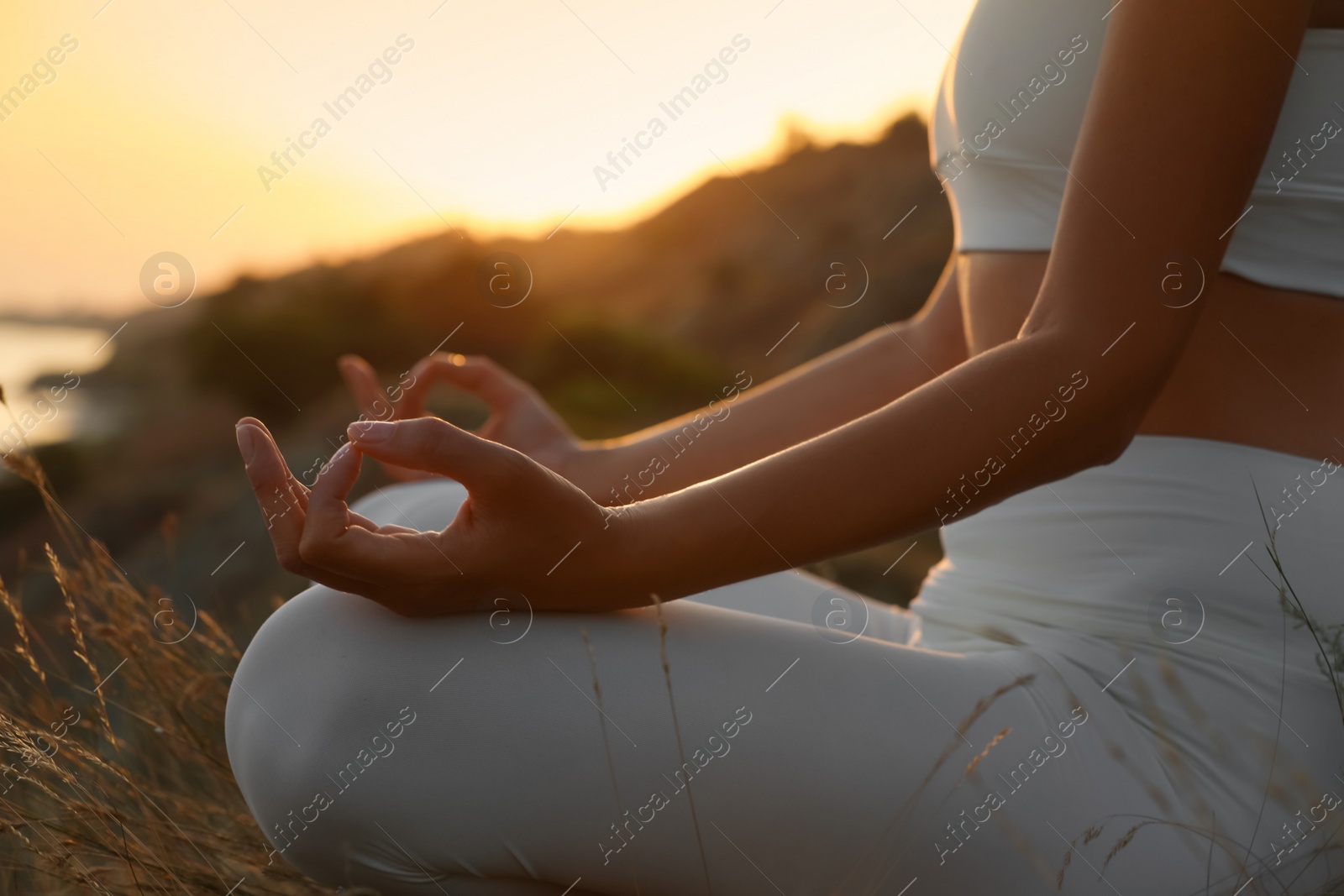 Photo of Woman meditating outdoors at sunset, closeup view