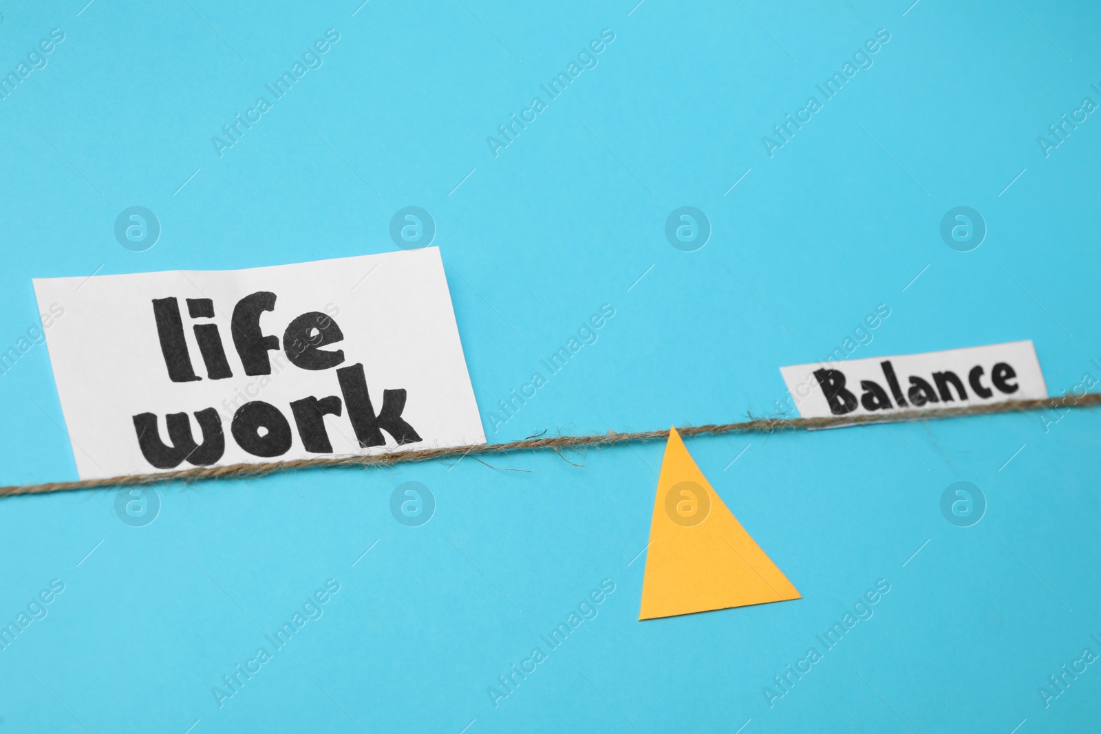Photo of Paper triangle, rope and words Life, Work, Balance on light blue background