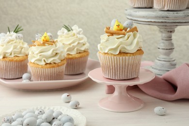 Photo of Tasty Easter cupcakes with vanilla cream on light wooden table