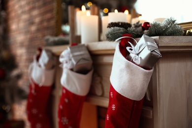 Photo of Decorative fireplace with Christmas stocking and gifts in stylish room interior