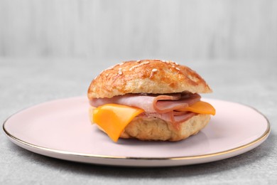 Photo of Delicious bagel with ham and cheese on light grey table