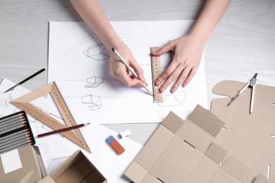 Photo of Woman creating packaging design at light wooden table, top view