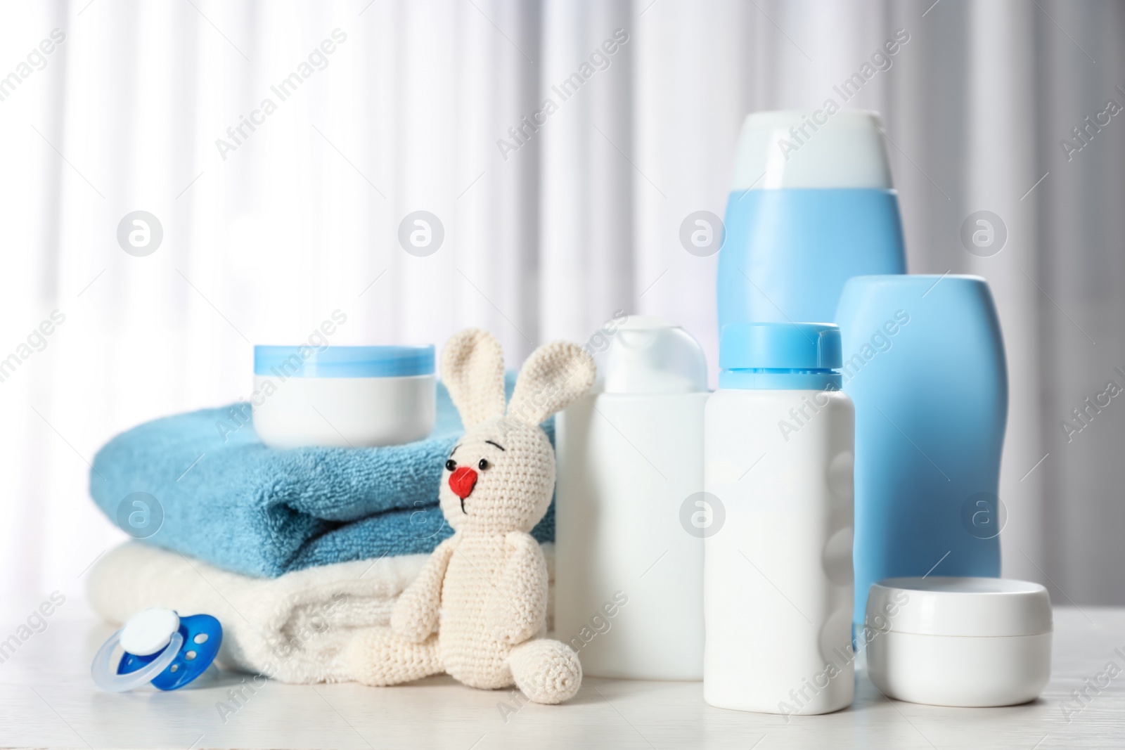 Photo of Baby cosmetic products, toy and towels on table indoors