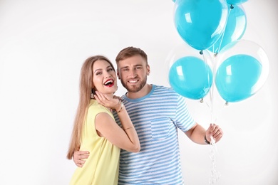 Young couple with air balloons on white background