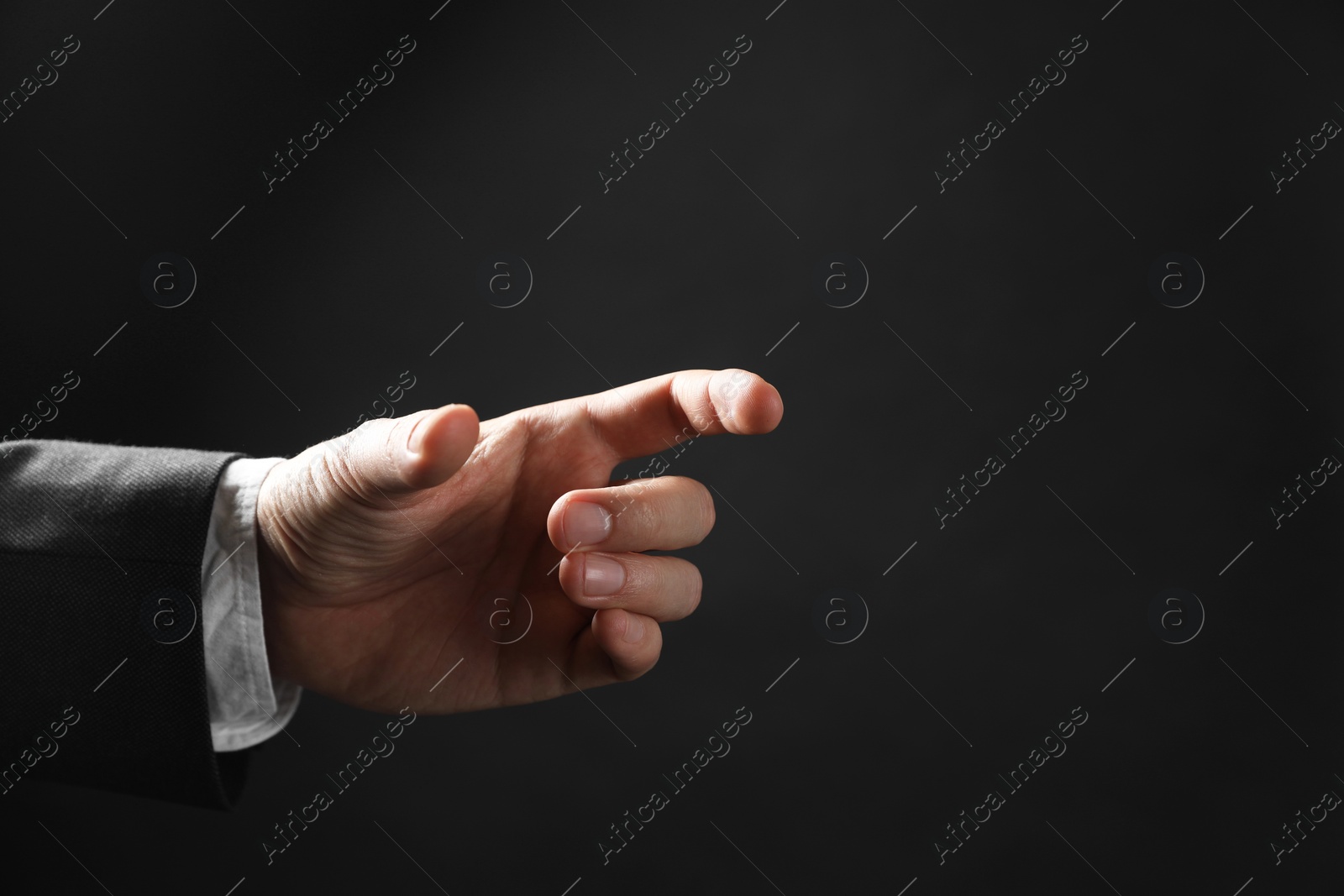 Photo of Man holding something in hand on black background, closeup. Space for text