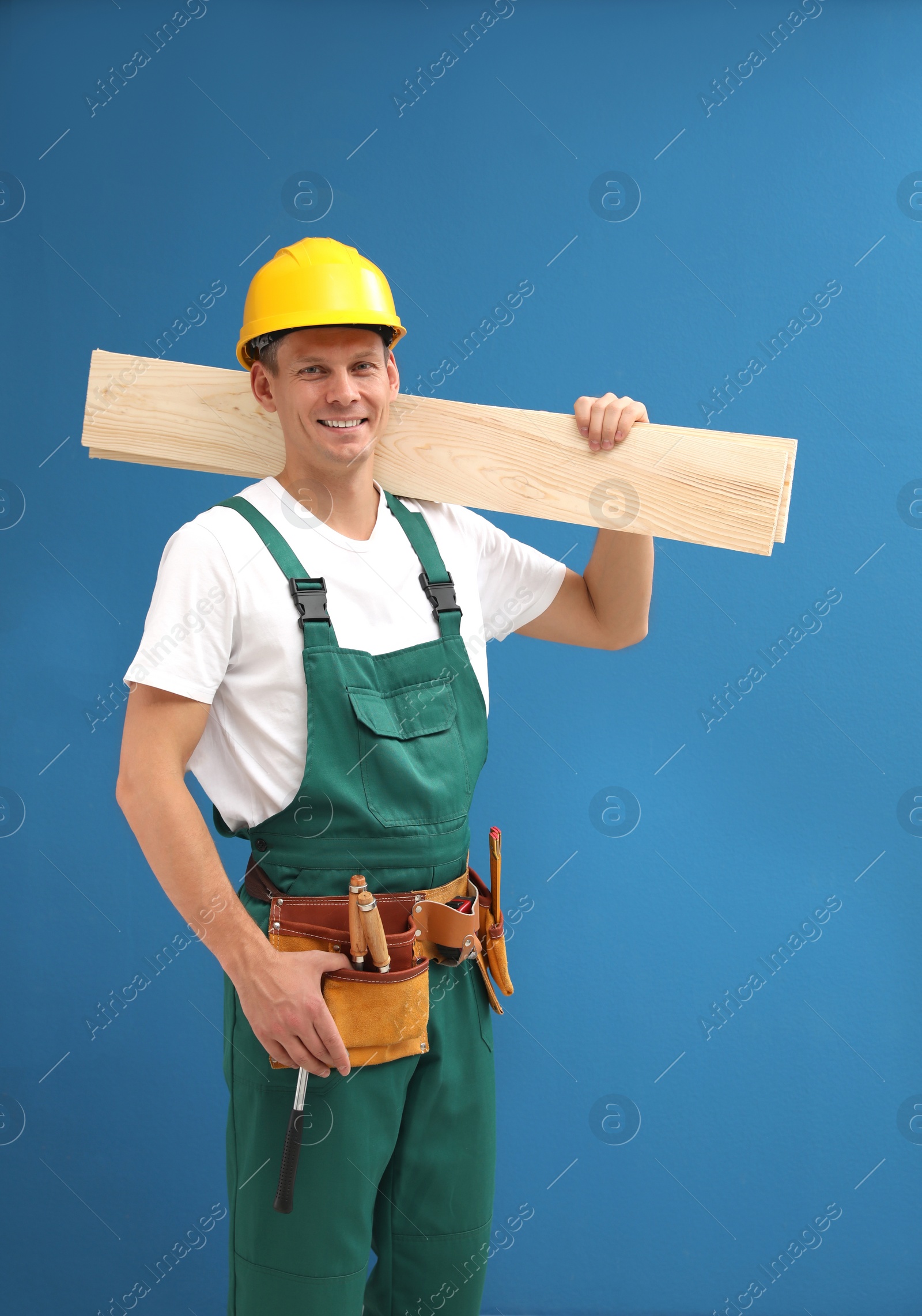 Photo of Handsome carpenter with wooden planks on blue background