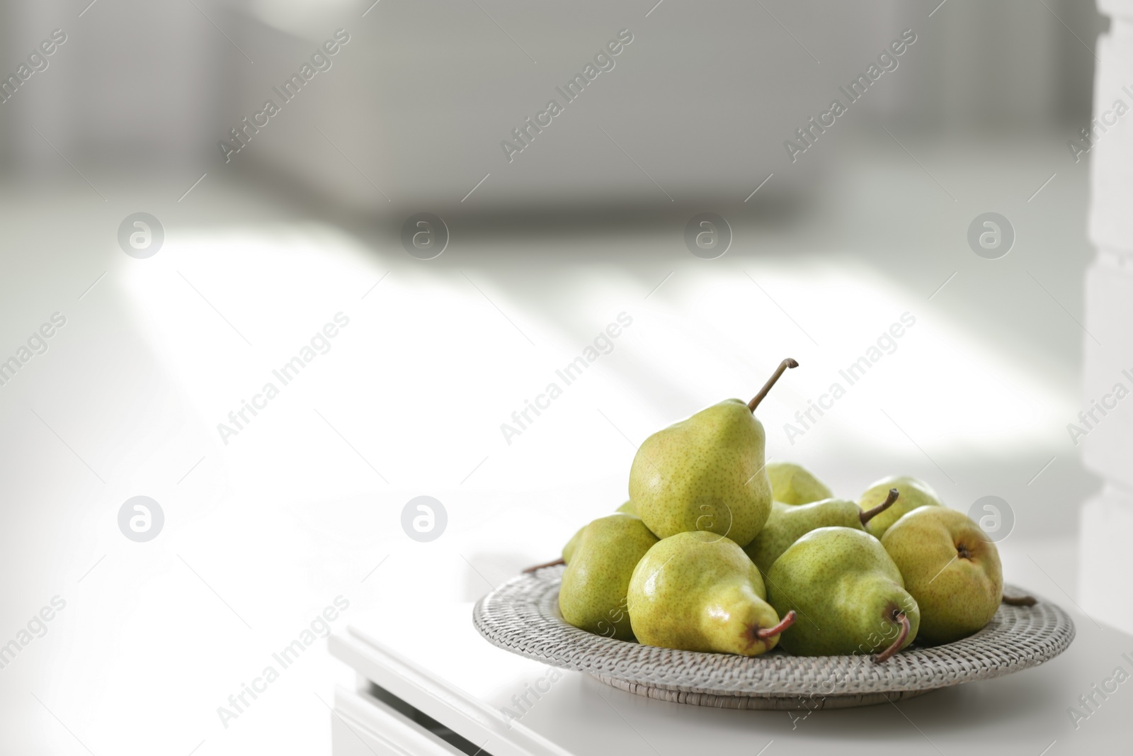 Photo of Fresh ripe pears on white table in room. Space for text