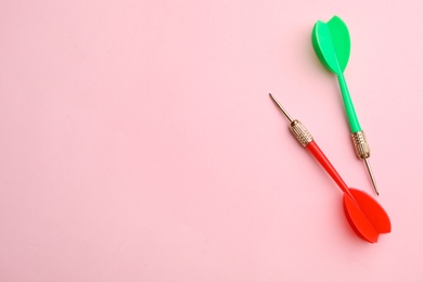 Photo of Plastic dart arrows on pink background, flat lay with space for text