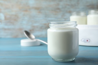 Photo of Glass jar with tasty yogurt on blue wooden table. Space for text