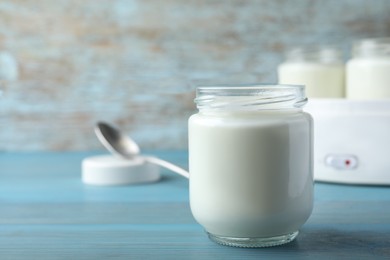 Glass jar with tasty yogurt on blue wooden table. Space for text