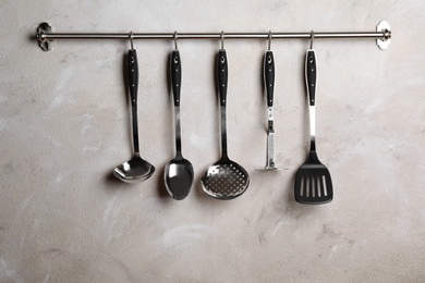 Rack with clean kitchen utensils on color wall