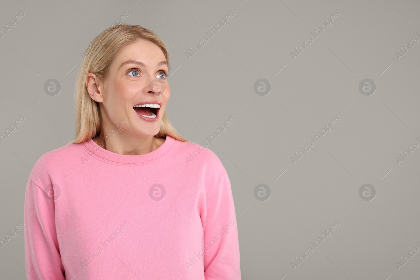 Photo of Portrait of happy surprised woman on grey background, space for text