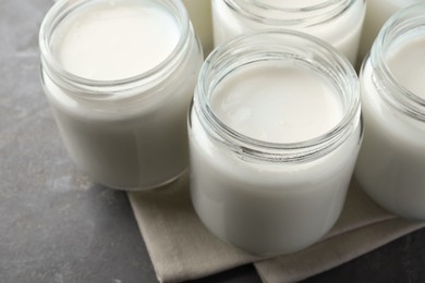 Photo of Tasty yogurt in glass jars on grey table, closeup