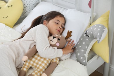 Cute girl in pajamas sleeping with toy deer at home