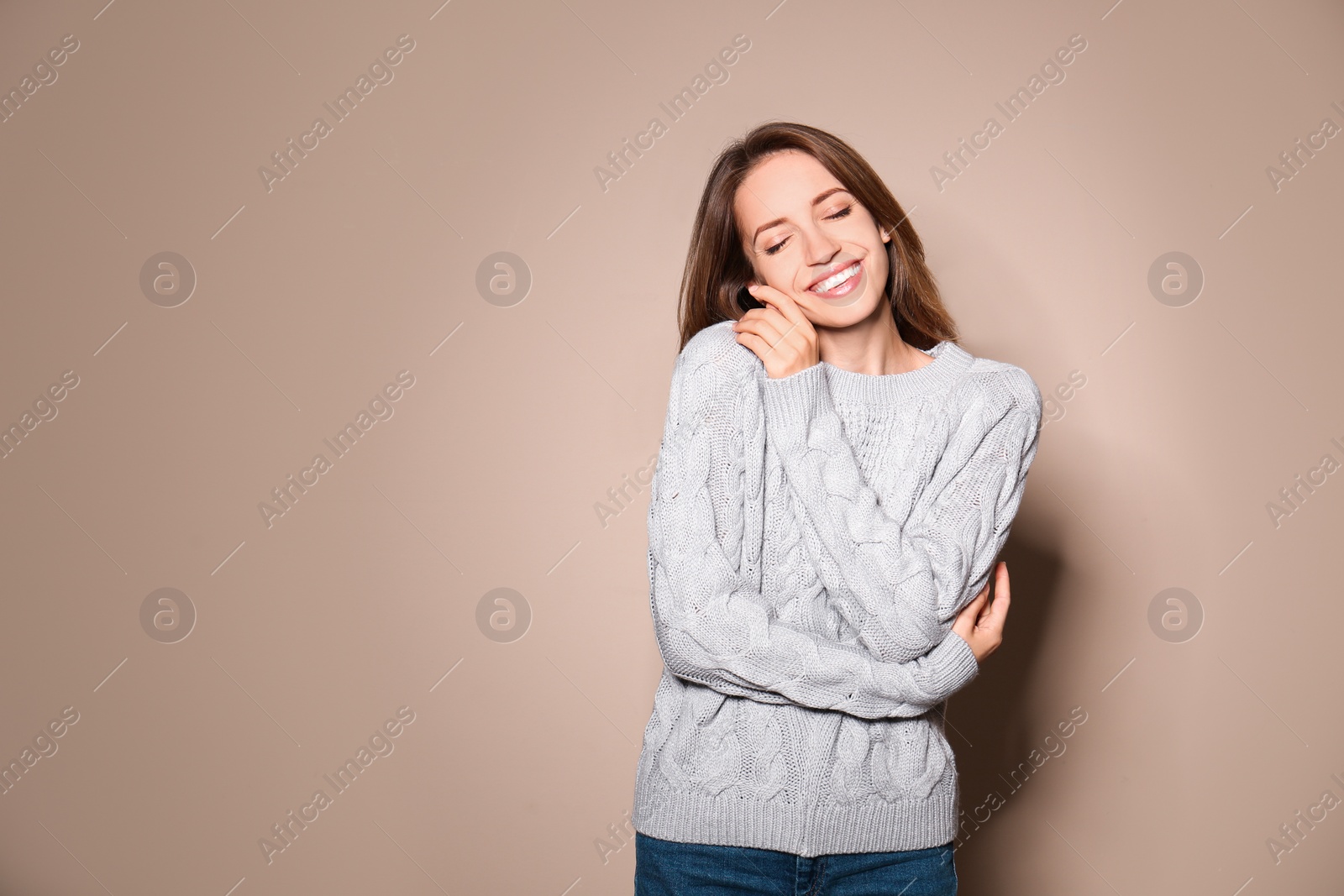 Image of Happy young woman wearing warm sweater on beige background. Space for text