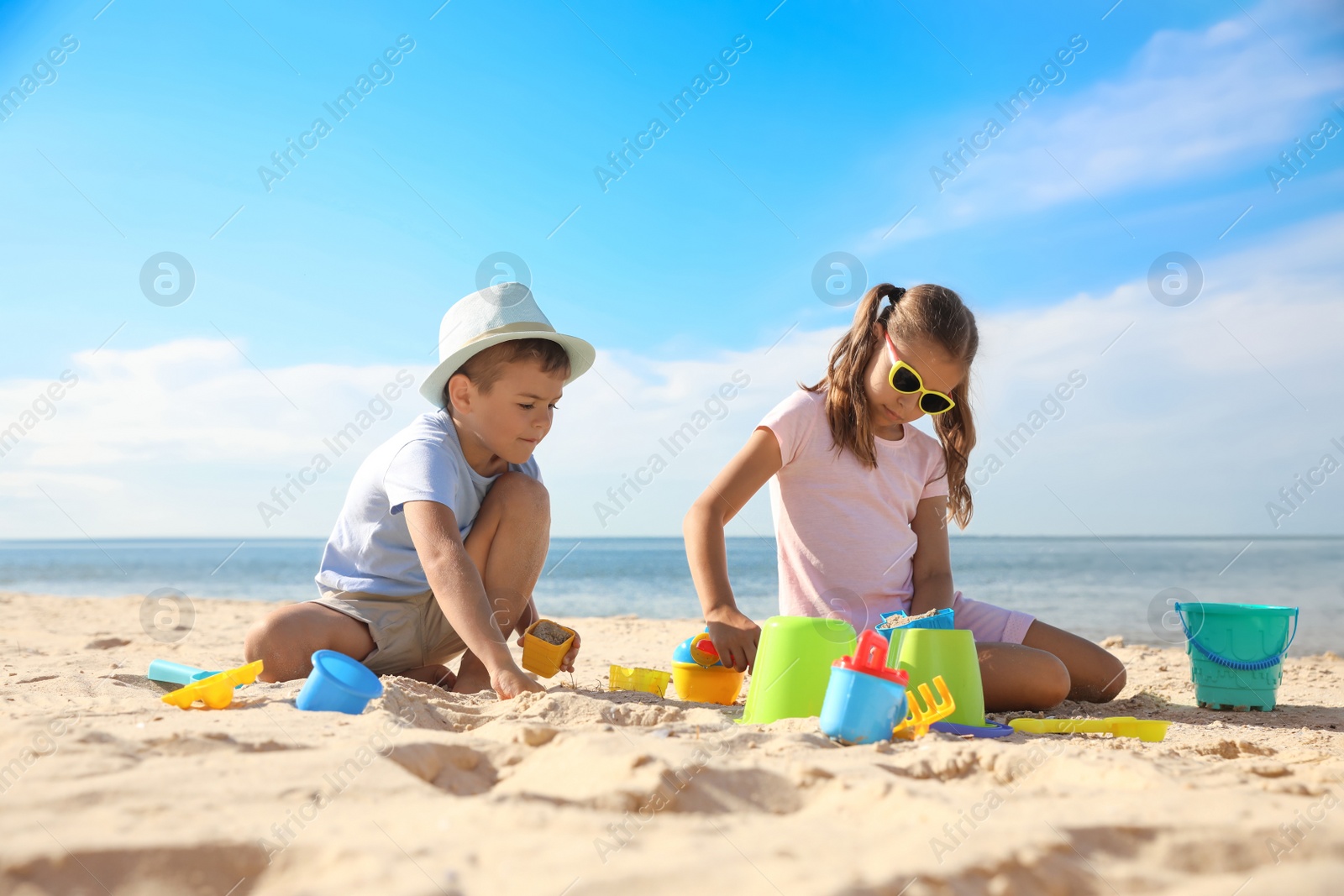 Photo of Cute little children playing with plastic toys on sandy beach