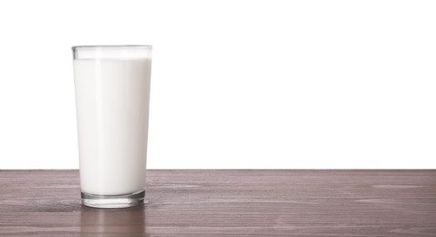 Photo of Glass of tasty milk on wooden table against white background