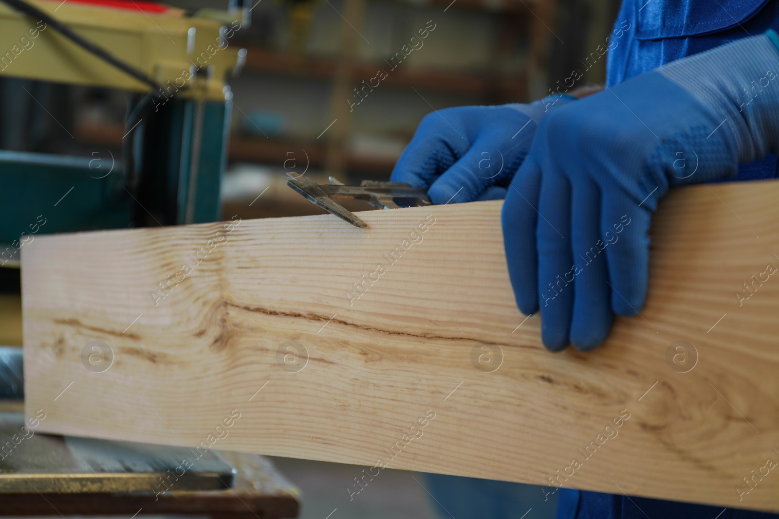 Photo of Professional carpenter measuring wooden board with sliding caliper in workshop, closeup