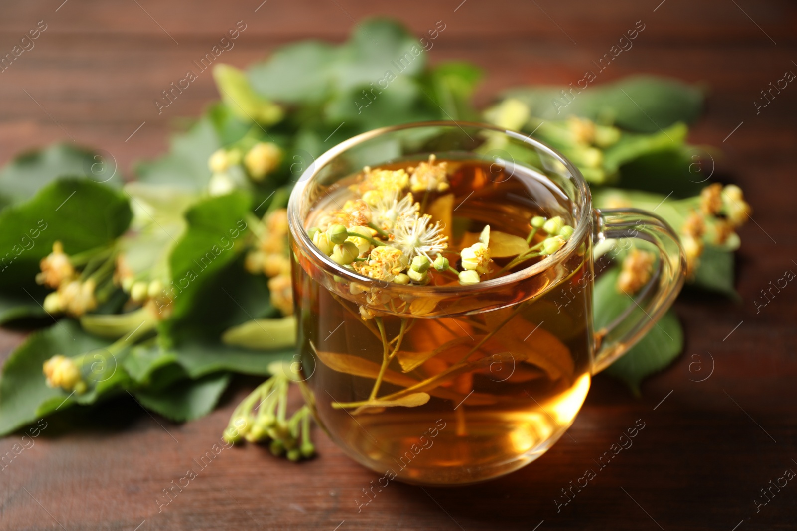 Photo of Cup of tea and linden blossom on wooden table