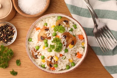 Photo of Bowl of delicious rice with vegetables on wooden table, flat lay