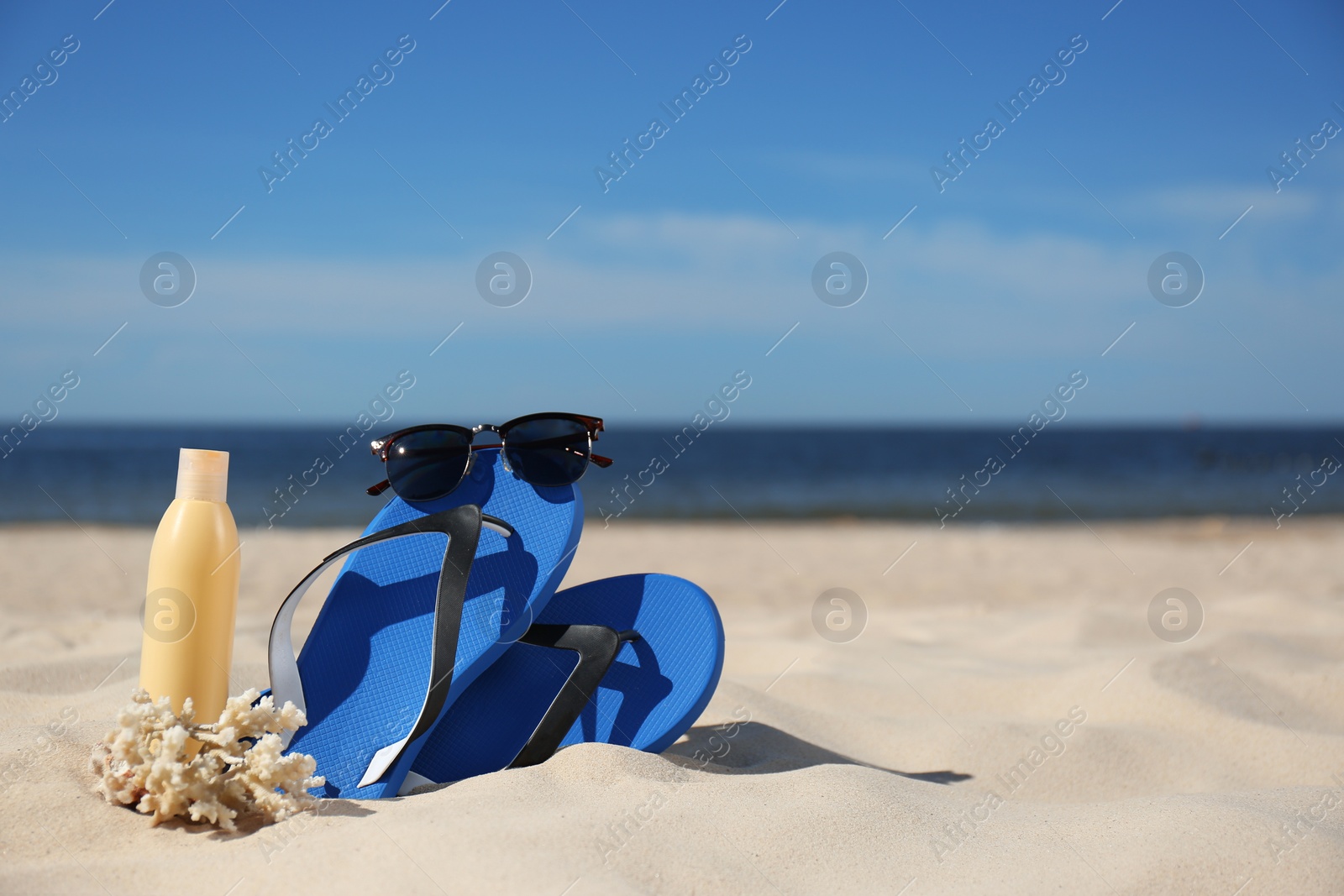 Photo of Stylish beach accessories for summer vacation on sand near sea. Space for text