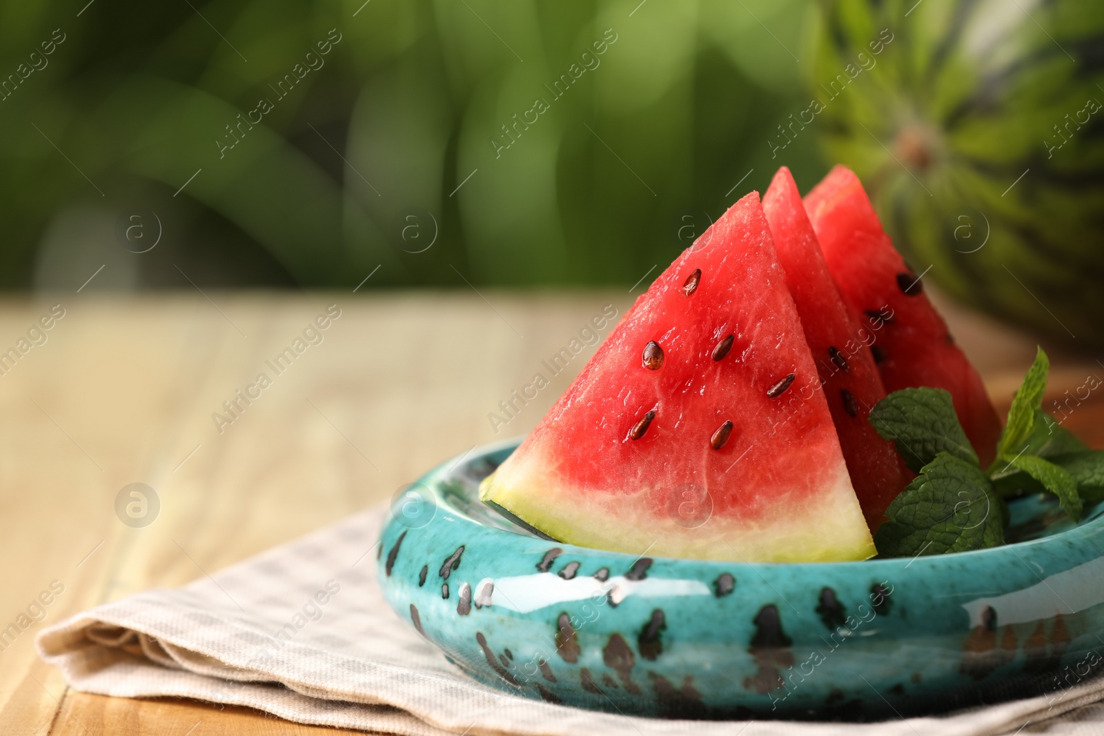 Photo of Slices of delicious ripe watermelon on wooden table outdoors, closeup. Space for text