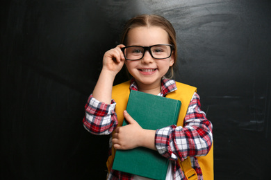 Photo of Cute little child wearing glasses near chalkboard. First time at school