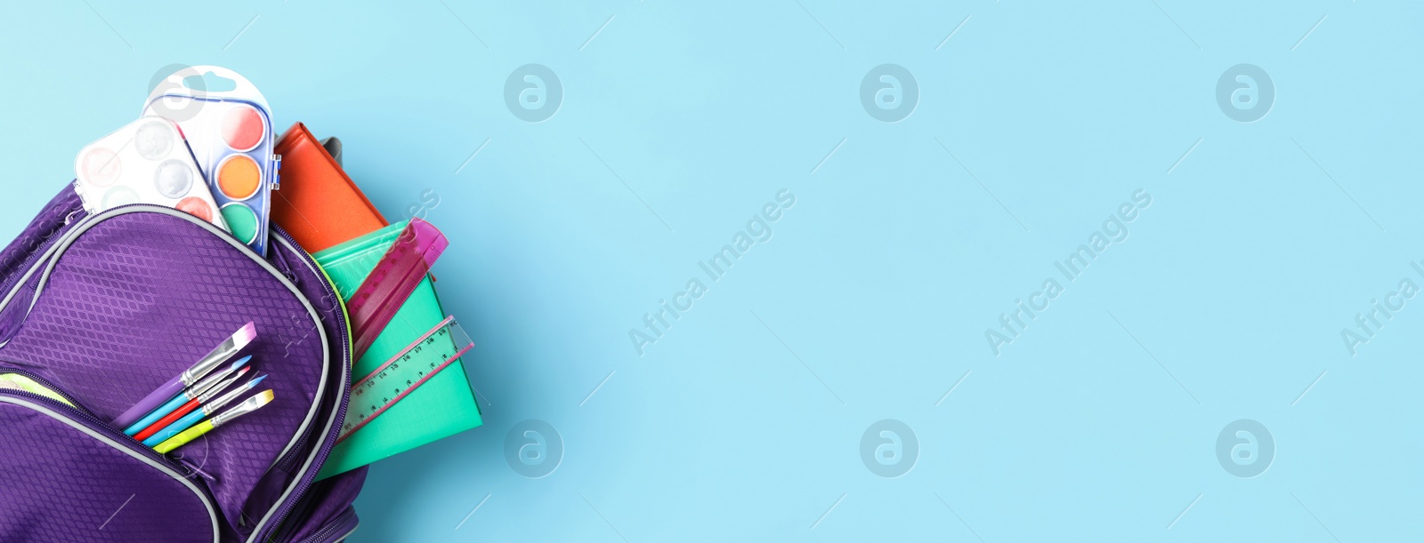 Image of Stylish backpack with different school stationery on light blue background, top view and space for text. Banner design