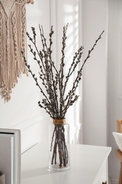 Photo of Glass vase with pussy willow tree branches on white table indoors