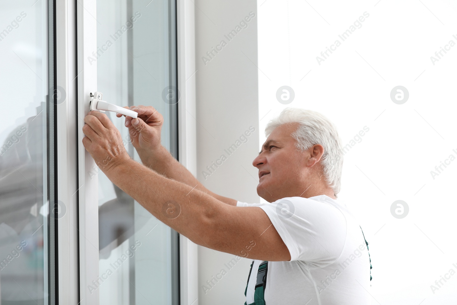 Photo of Mature construction worker repairing plastic window indoors