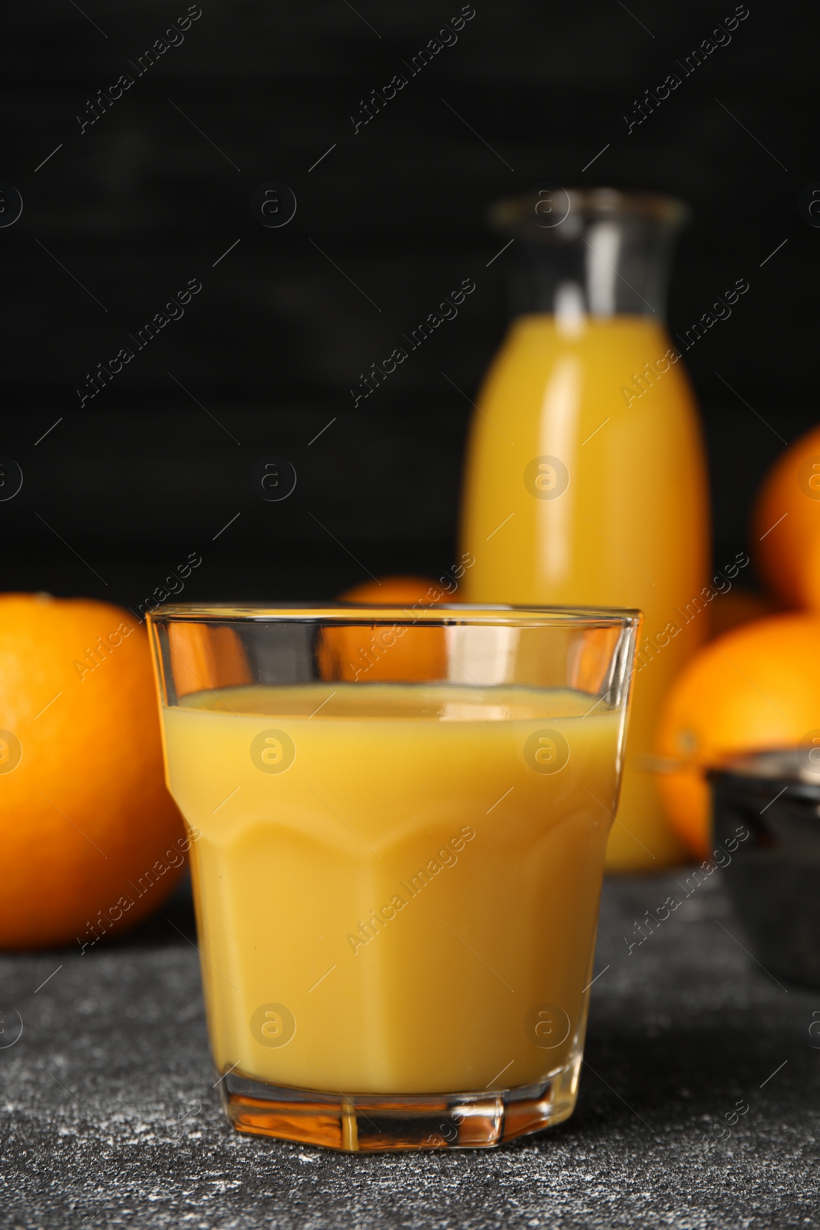 Photo of Tasty fresh oranges and juice on black table, closeup