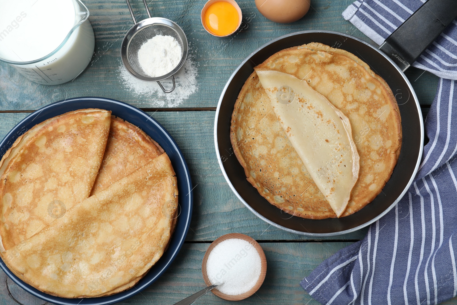 Photo of Flat lay composition with thin pancakes on blue wooden table