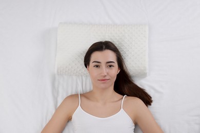 Photo of Woman lying on orthopedic pillow in bed, top view