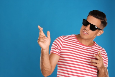 Photo of Handsome man wearing sunglasses on blue background