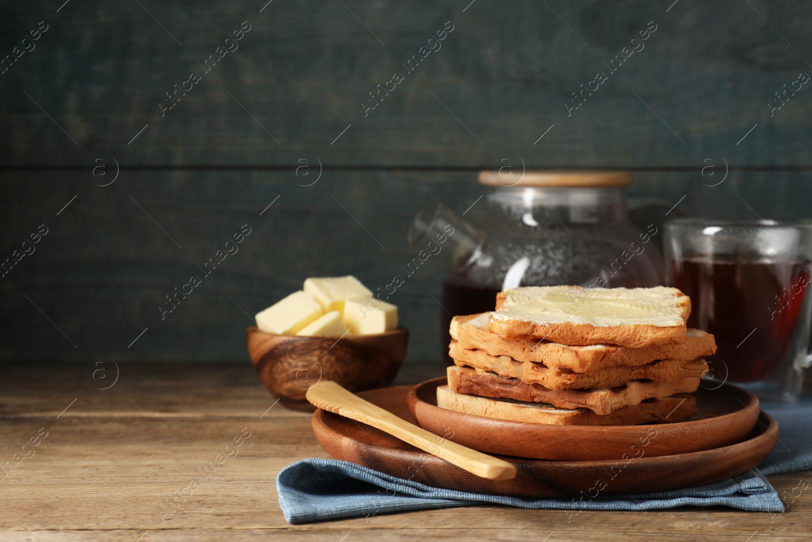 Photo of Tasty toasts with butter served on wooden table. Space for text
