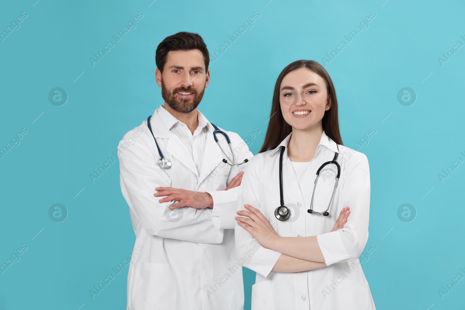 Photo of Nurses in medical uniforms with stethoscopes on light blue background