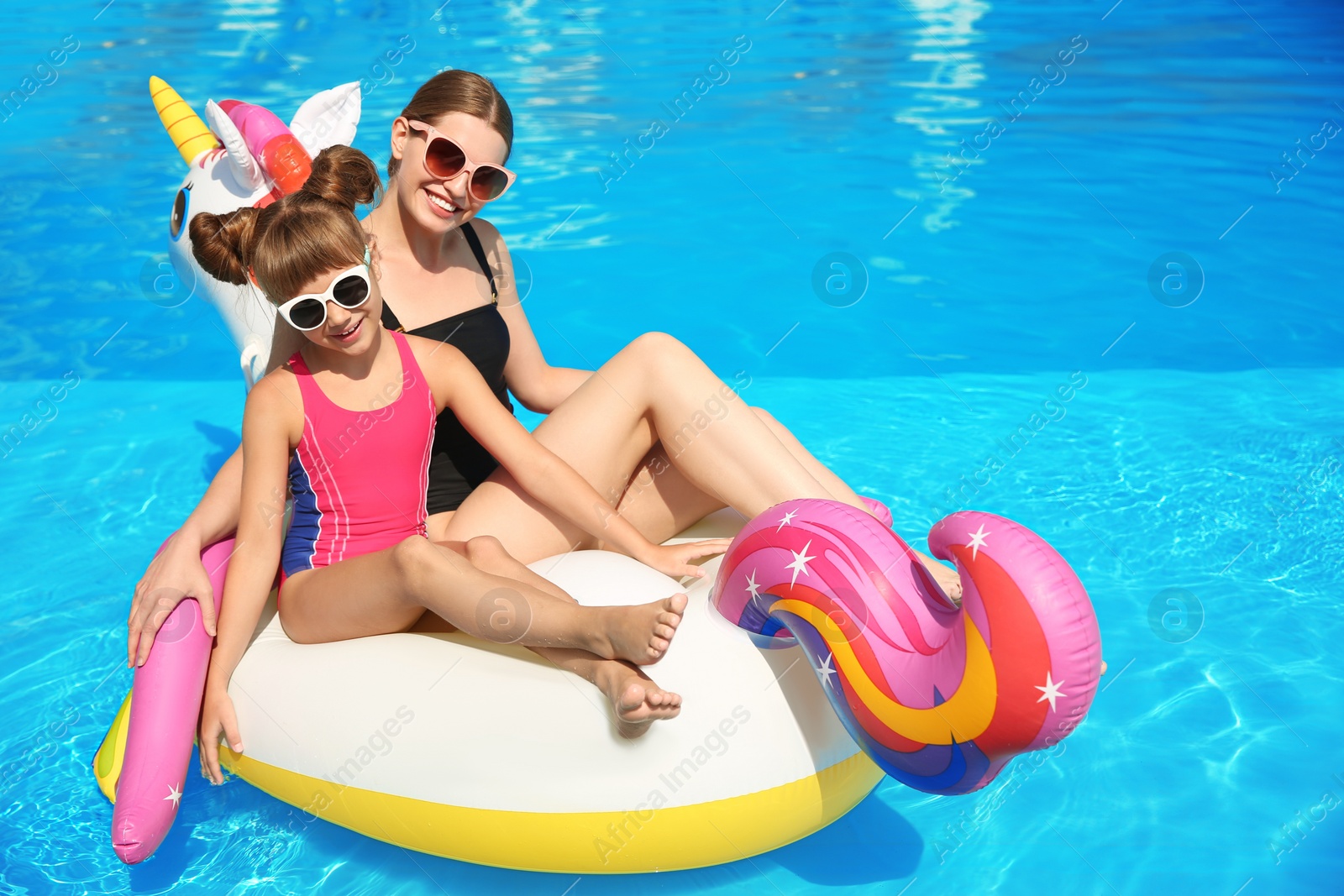 Photo of Mother and daughter on inflatable mattress in swimming pool. Family vacation