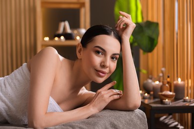 Spa therapy. Beautiful young woman lying on massage table in salon, space for text