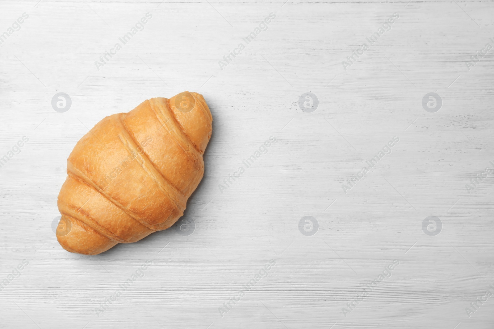 Photo of Tasty croissant on wooden background, top view