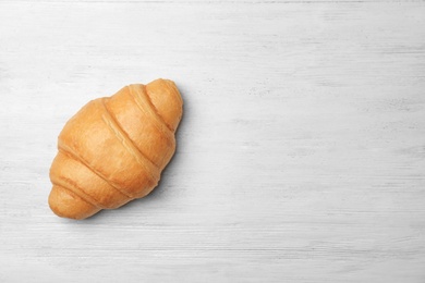 Photo of Tasty croissant on wooden background, top view