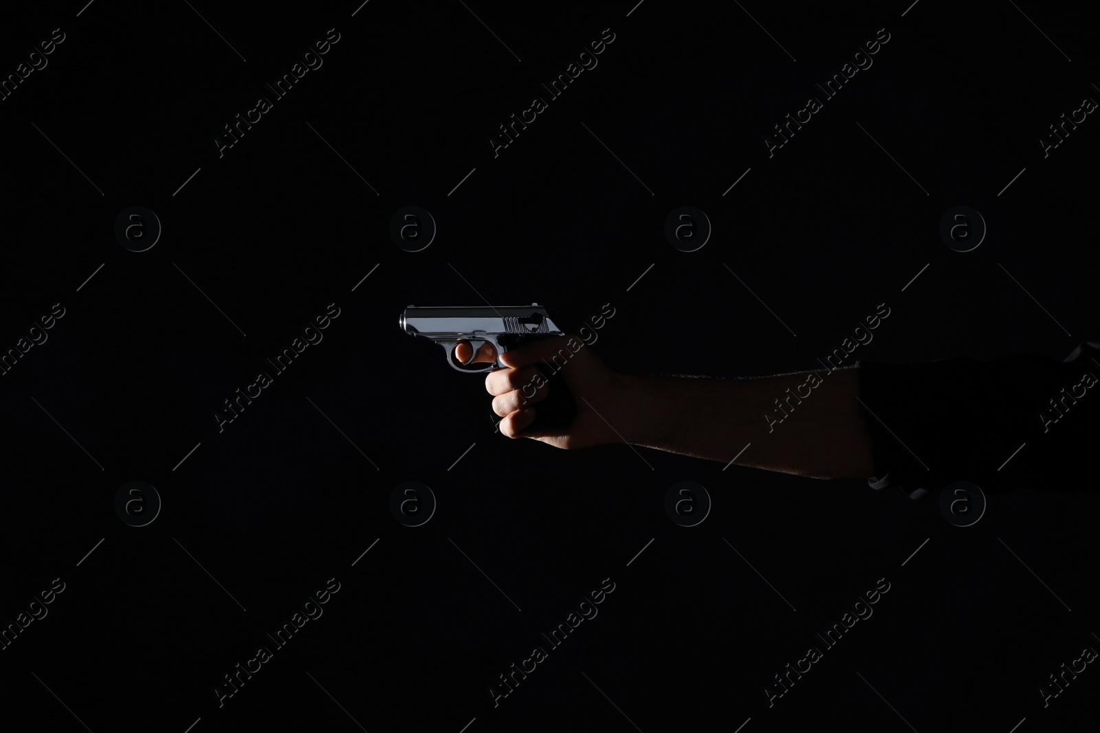 Photo of Professional killer with gun on black background, closeup