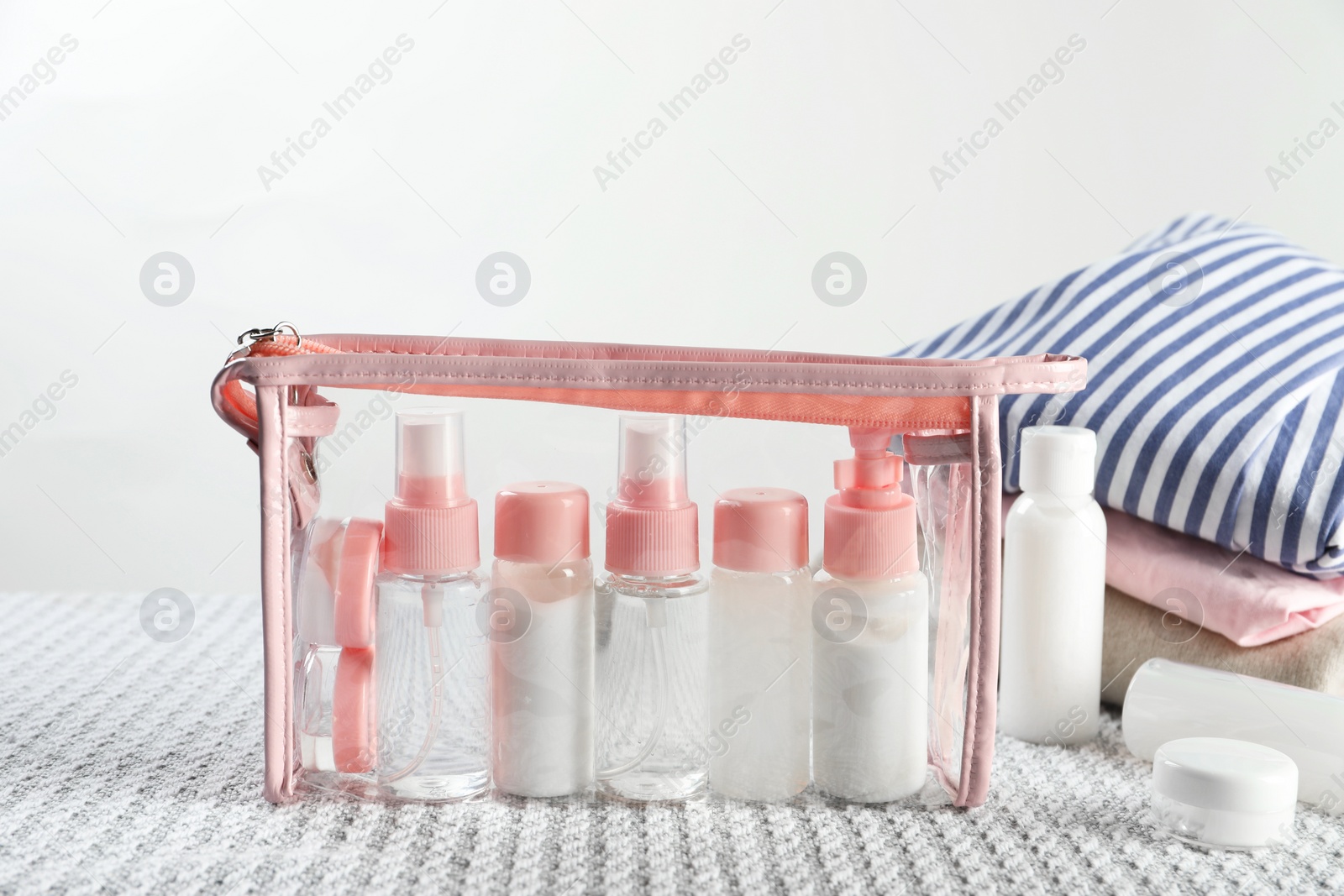 Photo of Cosmetic travel kit with plastic bag on bed indoors