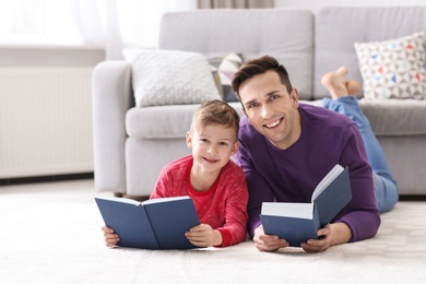 Photo of Dad and his son reading books at home