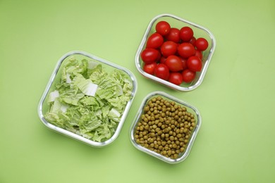 Photo of Glass containers with different fresh products on light green background, flat lay