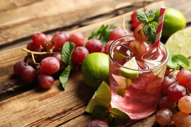 Photo of Refreshing drink with soda water, grapes, lime and mint on wooden table. Space for text