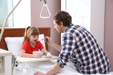 Photo of Man feeding his little child with soup in hospital